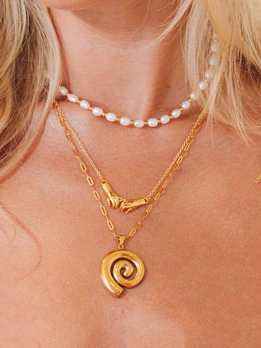Gold spiral pendant necklace with pearl necklace on a person