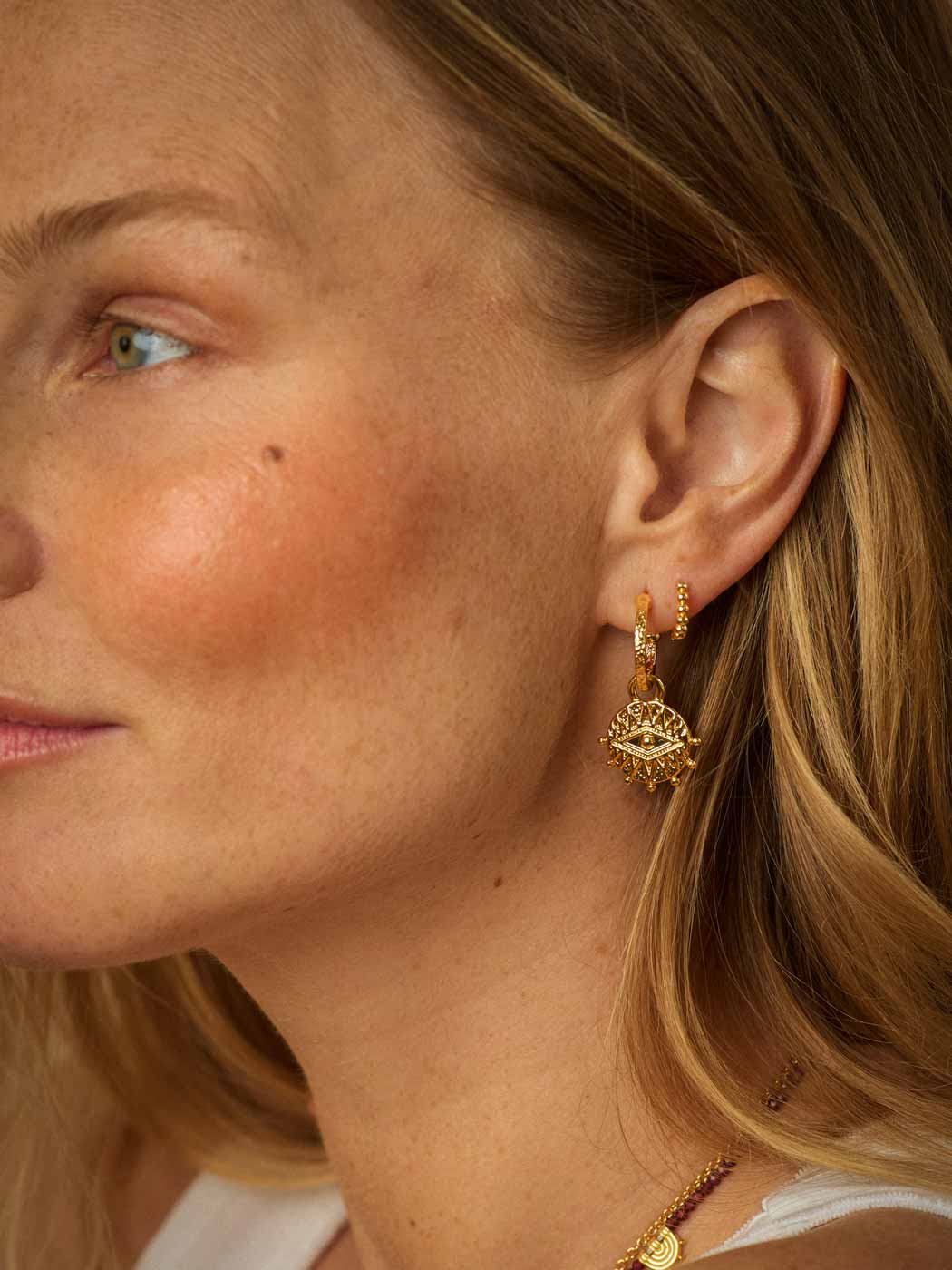 gold beaded delicate huggies paired with hoops on ear
