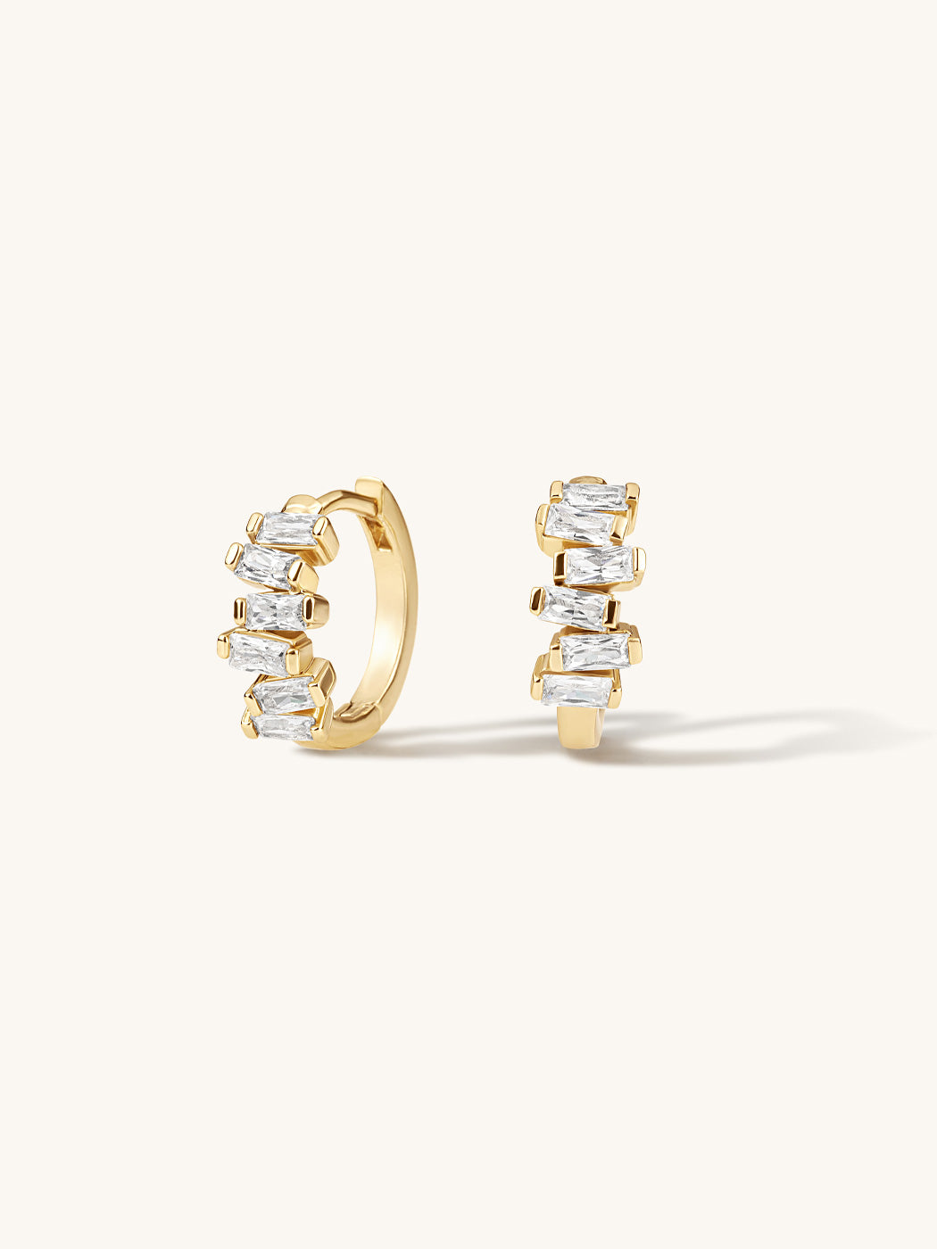 Gold hoop earrings with clear gemstones on a white background