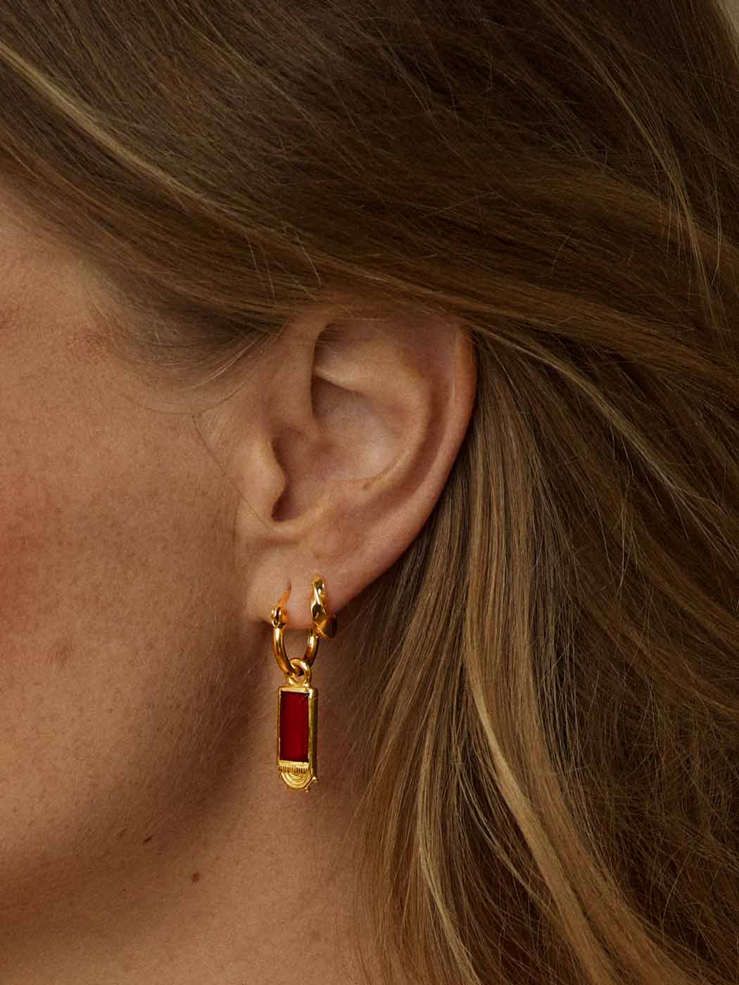 dainty gold huggies with twisted detail paired with red hoop on ear