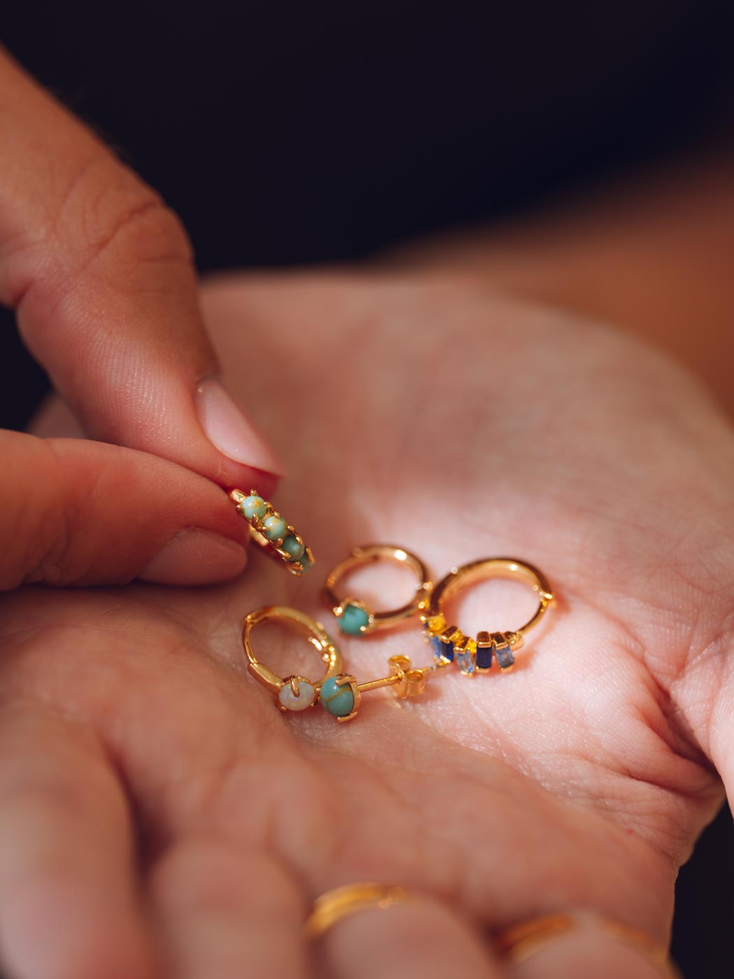 range of gemstones huggies on palm of hand