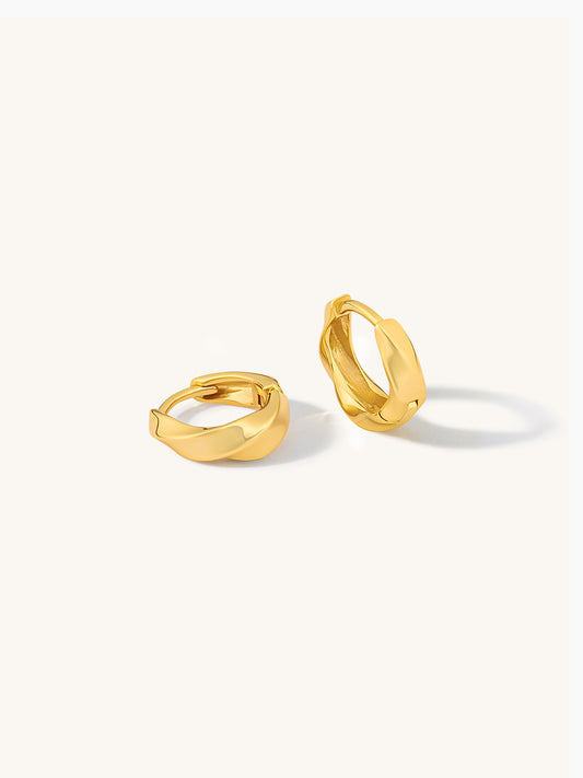 Pair of gold twist huggie earrings on a white background
