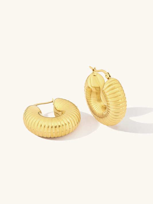 Statement ridged gold hoop earrings on a white background