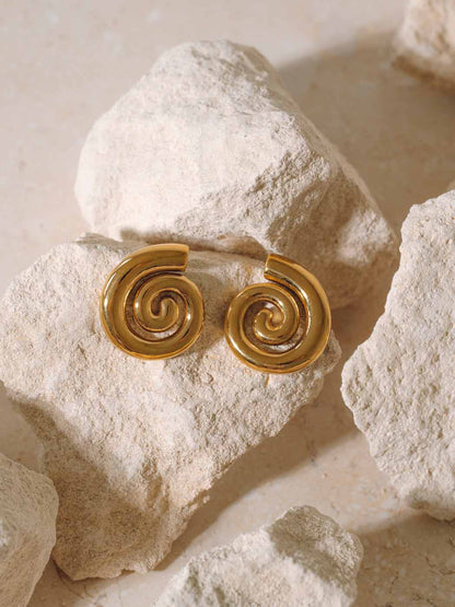 statement gold swirl stud drop earrings on rocks