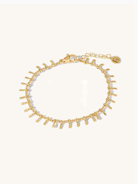 Gold bracelet with small bar texture on a white background