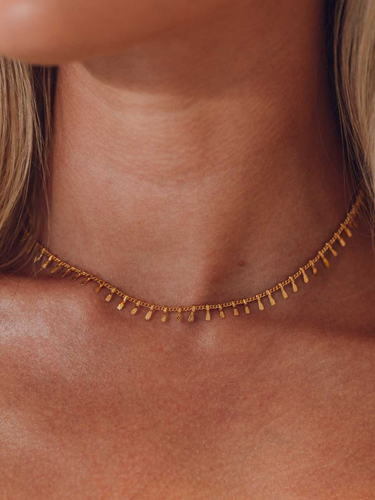 Gold fishhook necklace on a person's neck