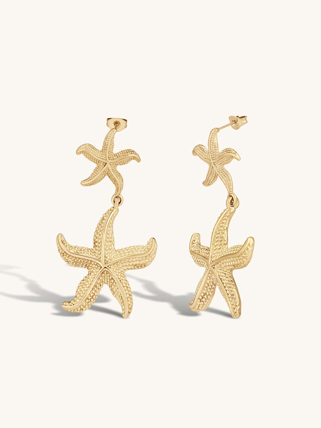 Gold statement starfish drop earrings on a white background