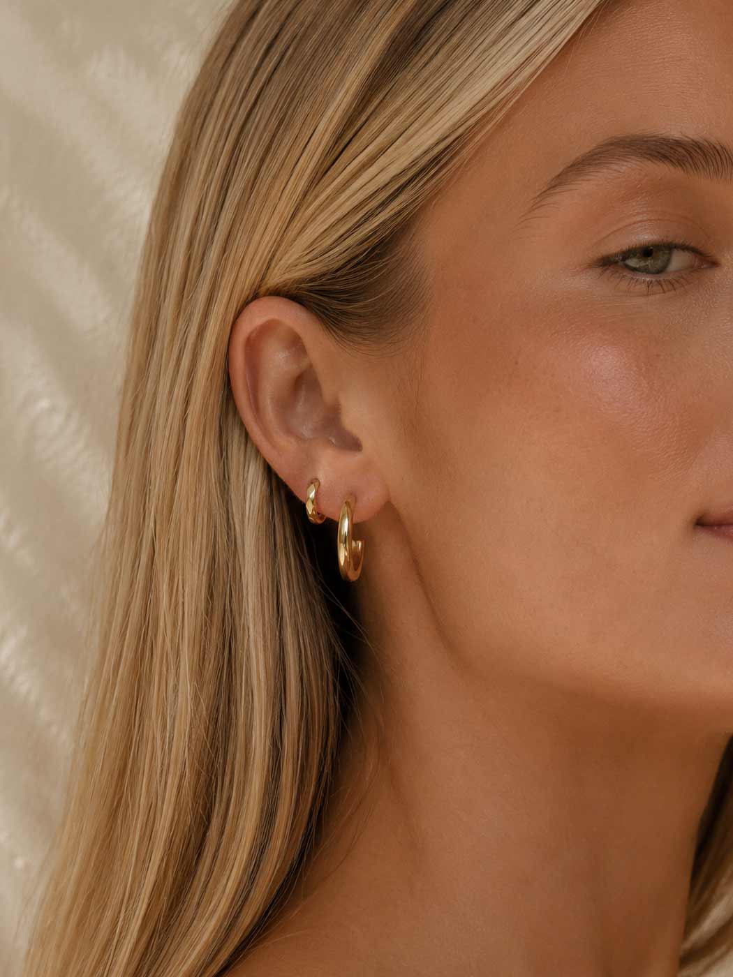 faceted gold huggie in second piercing of blonde woman