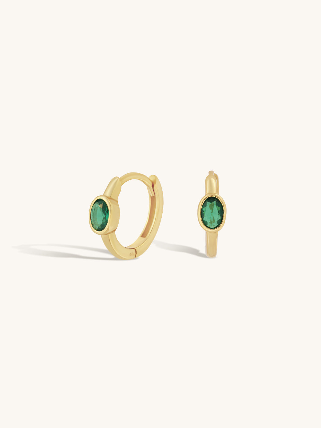 oval emerald gemstone set on simple gold sleek huggie