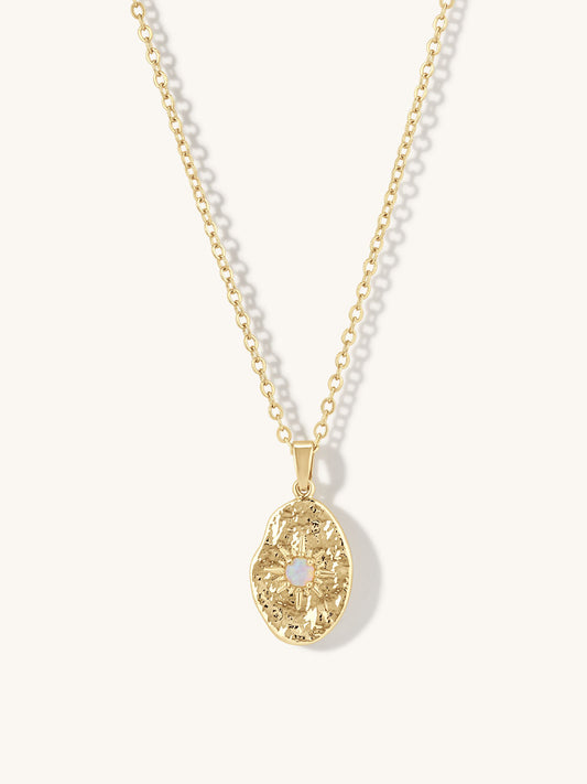 gold textured pendant necklace with small opal setting in center on white background