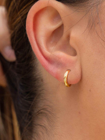 minimal faceted gold huggies on ear close up
