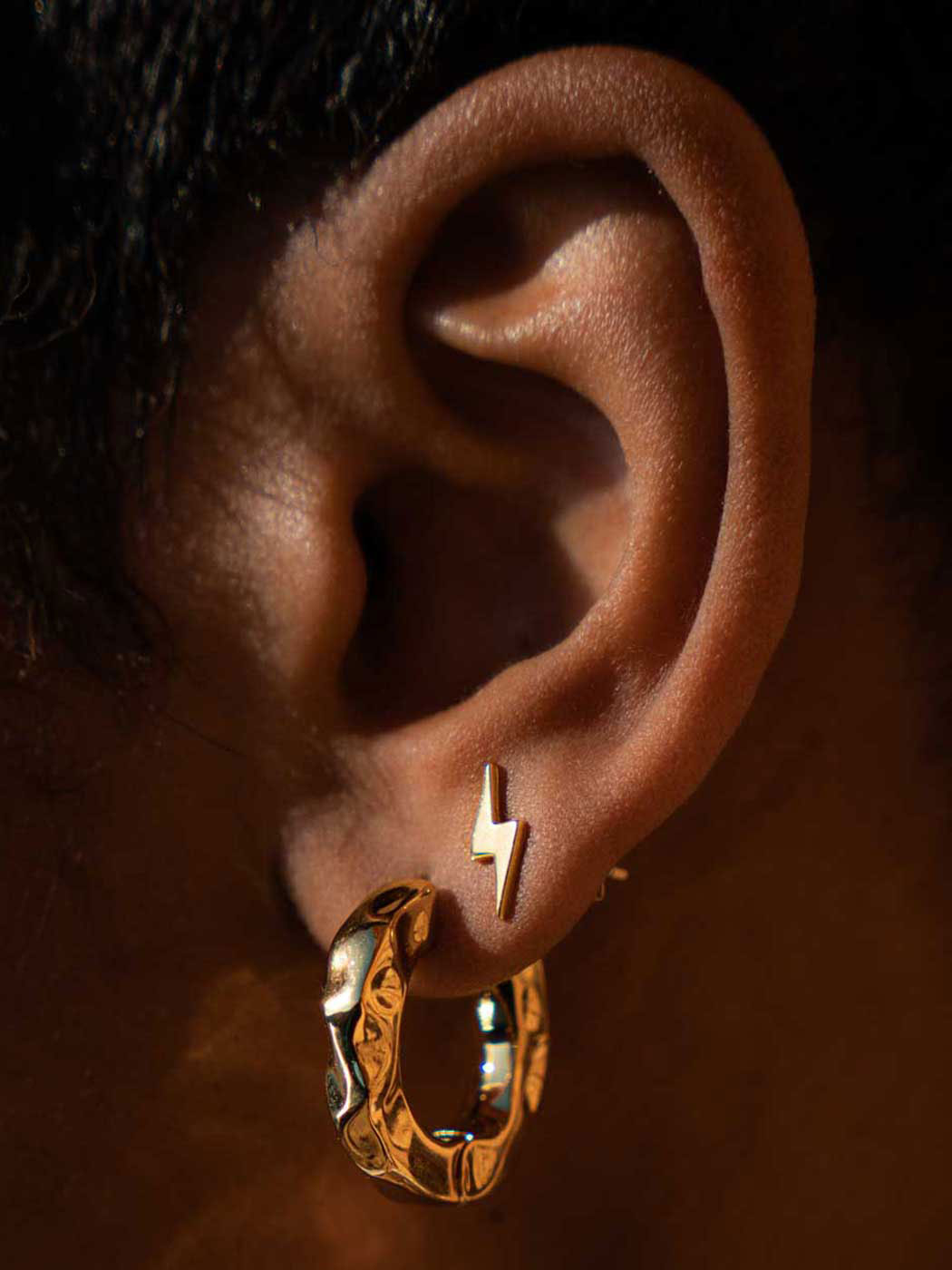 close up of small gold lightning shaped stud