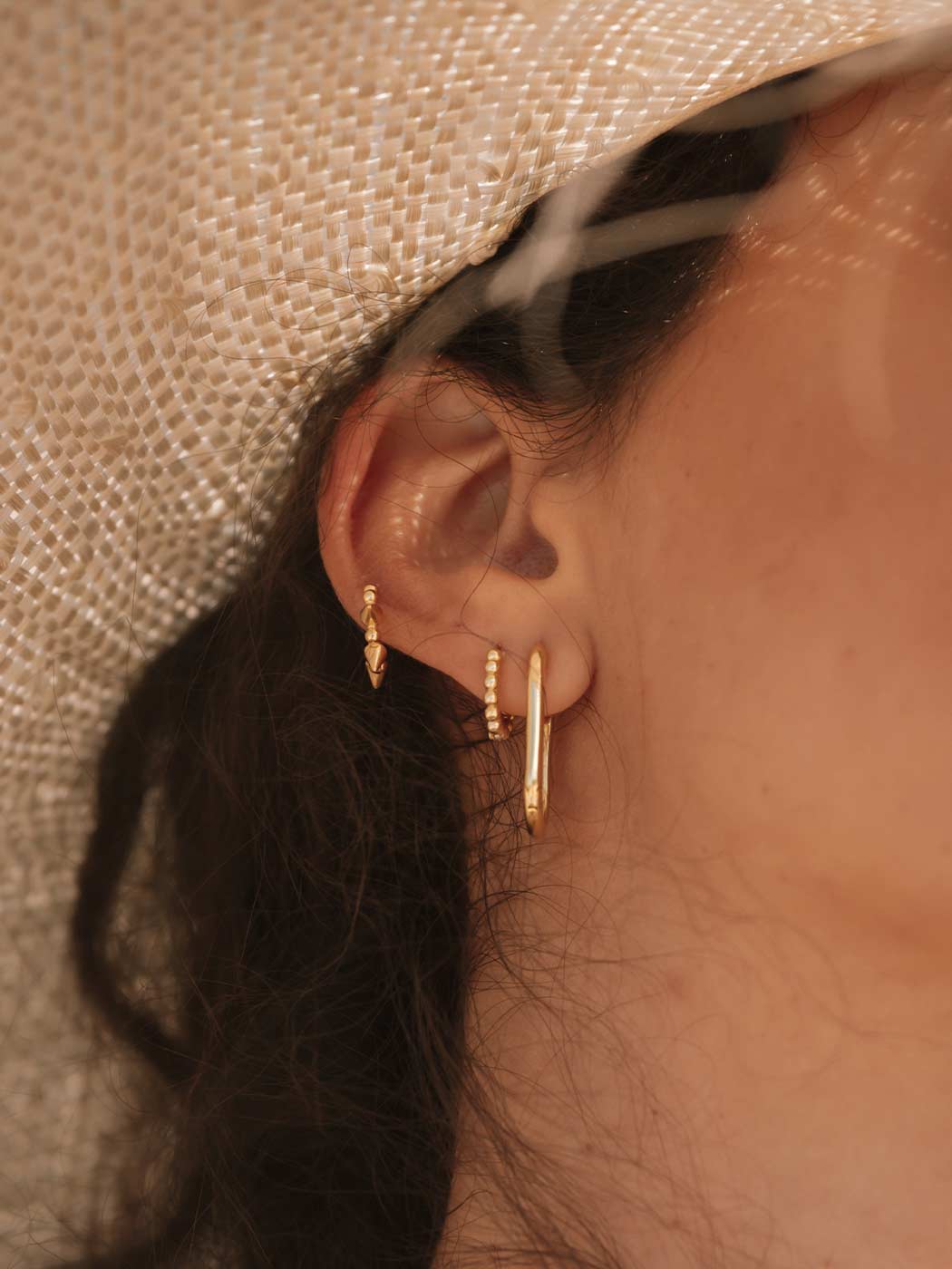 gold beaded delicate huggies in a set on an ear